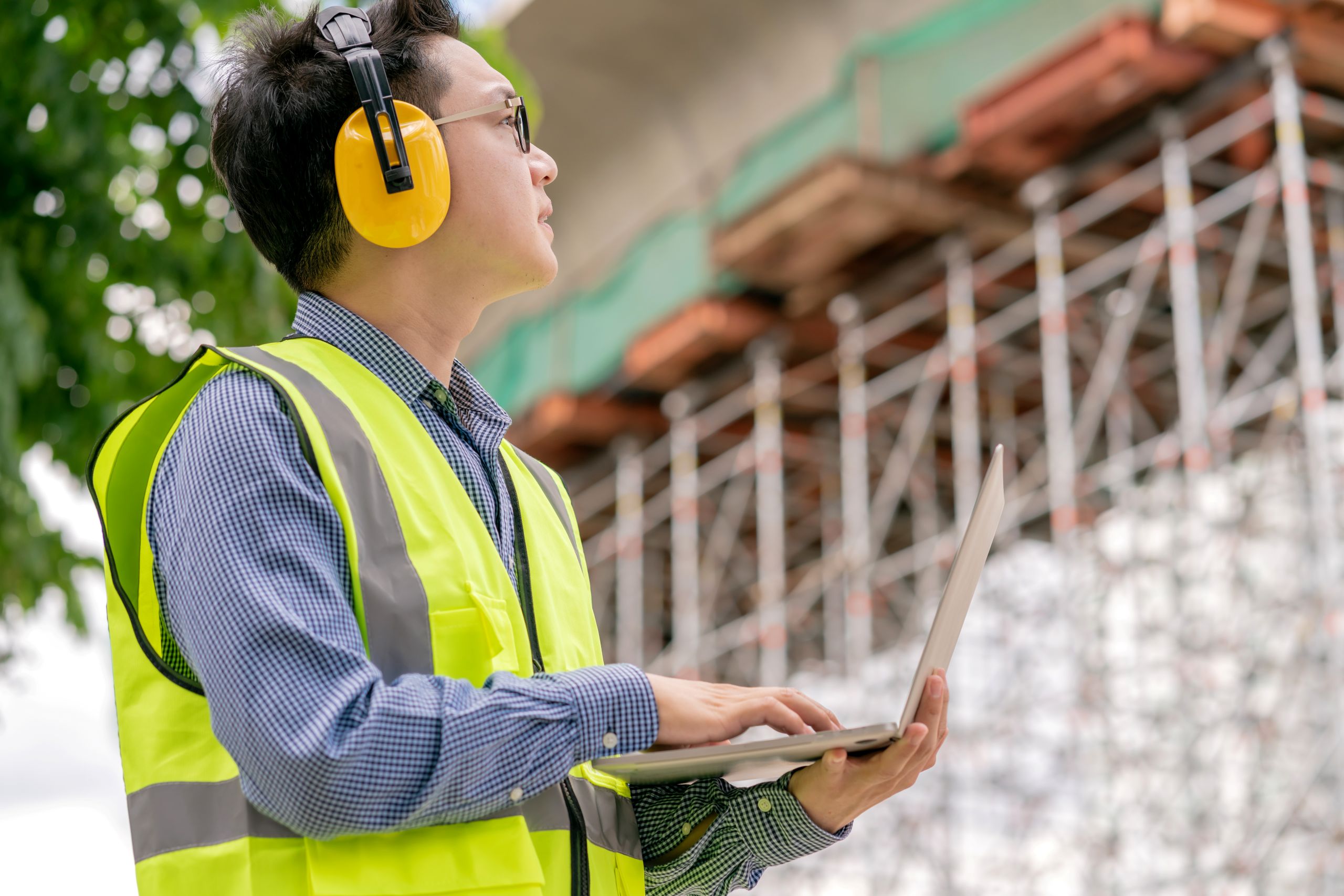 Site manager monitoring construction progress with a laptop.